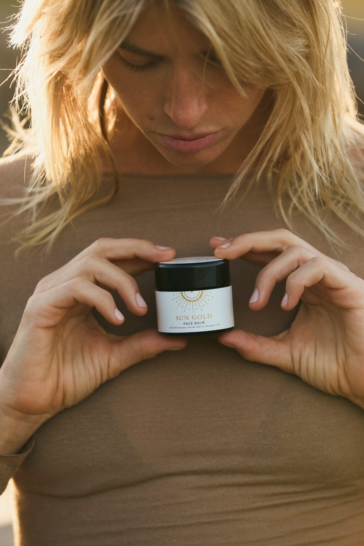Sun Gold face balm held in both hands in golden-hour light
